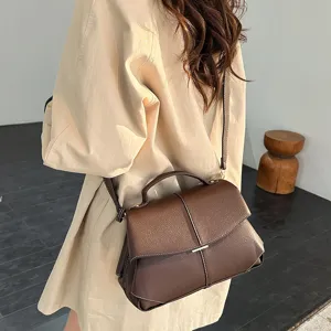 Vue détaillée d'un sac bandoulière élégant en cuir marron foncé avec coutures contrastées.
