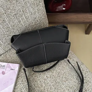 Vue détaillée du sac à main en cuir noir avec des coutures contrastées et des plis.