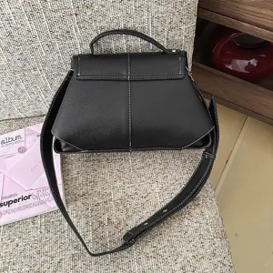 Sac bandoulière en cuir noir avec surpiqûres contrastées, design élégant et décontracté.