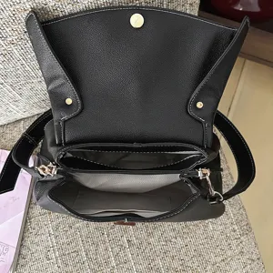 Vue détaillée de l'intérieur du sac à main en cuir noir, montrant compartiments et doublure.