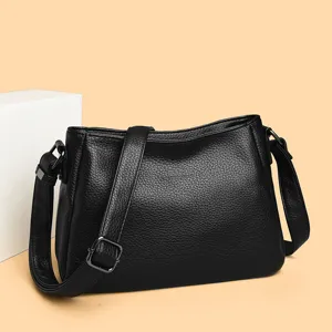 Close-up detail of the black leather shoulder bag showing the fine texture and strap.