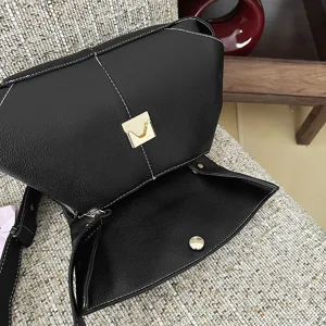 Gros plan détaillé du sac à main boston en cuir noir avec de élégantes surpiqûres blanches.