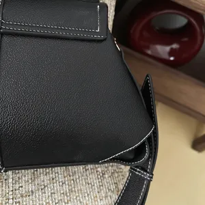 Sac bandoulière en cuir noir vue détaillée avec design plié géométrique et coutures blanches.