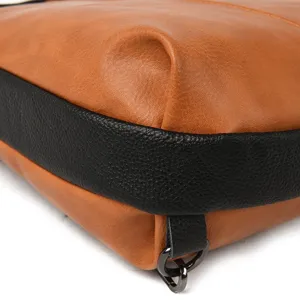 Detailed shot of color-block leather backpack corner, showing clear texture and metal ring.