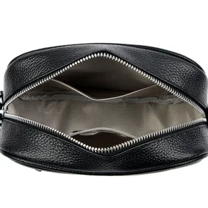 Black genuine leather crossbody bag interior view, featuring zippered pocket and fabric lining.
