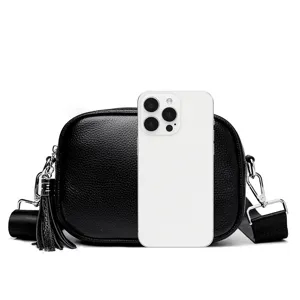 Detailed view of the black genuine leather crossbody bag featuring a chic tassel and wide strap.
