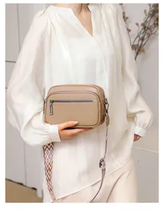 Sac bandoulière classique en cuir taupe avec sangle large à motifs et doubles compartiments zip.