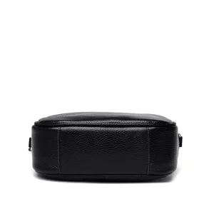 Black leather crossbody bag detail view showing the bottom structure and fine texture grain.