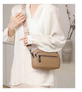 Sac bandoulière en cuir véritable avec sangle géométrique large et doubles fermetures.
