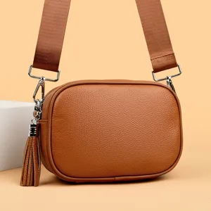 Leather crossbody bag detail view showing fine texture, hardware and tassel decoration.
