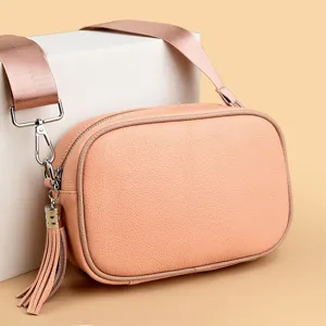 Chic pink leather camera bag detail, featuring a wide strap and elegant tassel pendant design.