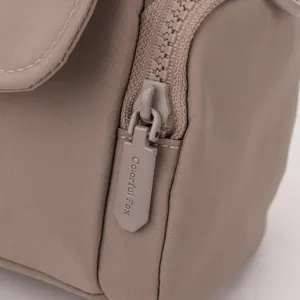 Detailed close-up shot of the brown women's crossbody bag zipper and fine stitching.