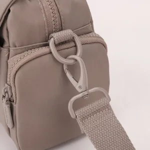 Detail shot of the nylon crossbody bag showing durable hardware buckle and zipper pull.