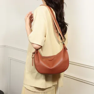 Detail shot of a brown leather slouchy shoulder bag worn by a model, casual style.