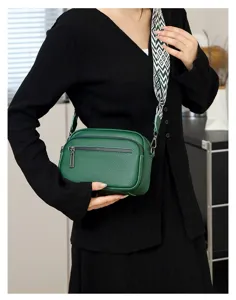 Détail de sac bandoulière en cuir vert avec cuir souple et large sangle géométrique.