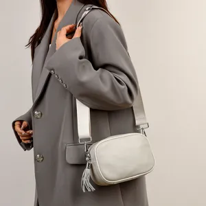 White leather crossbody bag detail, chic wide strap and tassel accent for women fashion style.