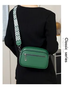 Vue détaillée du sac bandoulière en cuir vert sur le mannequin avec une sangle large et zips.