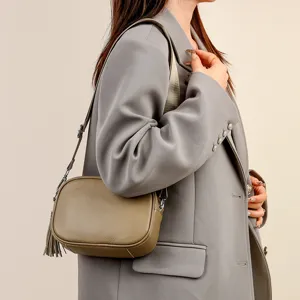 Detail view of a stylish khaki cross-body leather bag worn by model, modern design.