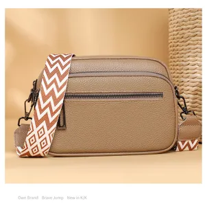 Gros plan d'un sac bandoulière en cuir marron avec sangle à motifs et doubles fermetures.