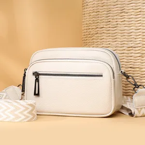 Élégant sac bandoulière en cuir beige avec large sangle et poche zippée pour femme chic.