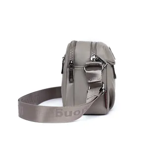 Side detail of the casual grey nylon crossbody bag, showing multi-zipper compartments and strap.