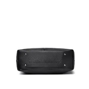 Black women's large capacity soft leather handbag bottom detail showcasing protective metal feet.