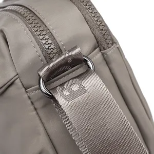 Close-up detail of casual nylon crossbody bag showing durable strap, metal ring and zipper.