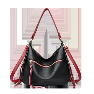 Detail view of the black leather shoulder bag featuring stylish red straps and gold zipper accents.