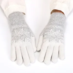 Close-up detail of winter women's warm knitted gloves featuring a classic snowflake design.