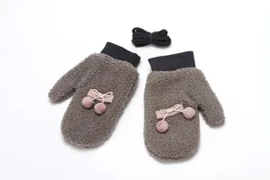 Detailed close-up of winter fleece gloves with double pom-poms and bow, cozy and soft.