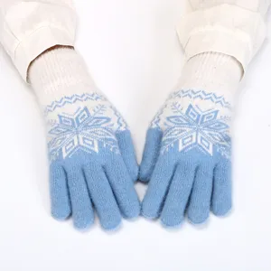 Close-up detail of winter knit thermal gloves with blue and white snowflake jacquard pattern.