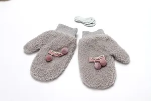 Grey winter fluffy mittens close up, plush fabric with cute pom pom bow and hanging rope.