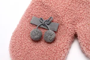 Close-up view of pink winter fleece warm gloves with cute grey ribbon and dual pom-pom decor.