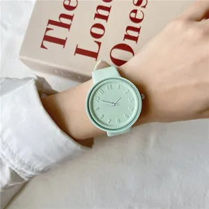 Macaron green silicone watch detail view, minimalist round dial with embossed numbers.