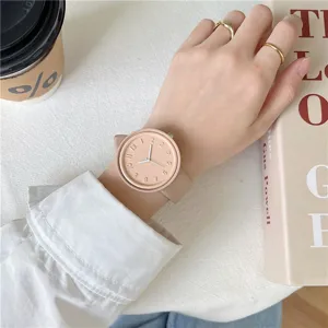 Detailed close-up of pink silicone watch worn on wrist with minimalist dial and numbers.