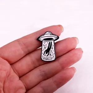 Detailed close-up of creative black and white UFO astronaut enamel pin badge accessory.