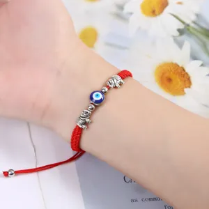 Gros plan sur le bracelet tressé en corde rouge mauvais œil avec des charms éléphants.