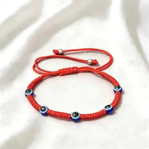 Vue détaillée du bracelet tressé rouge avec mauvais œil et perles de protection bleues.