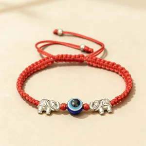Bracelet en cordon tressé rouge avec perle œil maléfique bleu et deux charms éléphant argent.