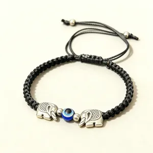 Gros plan sur les details du bracelet tisse noir avec pendentifs elephant et oeil bleu.