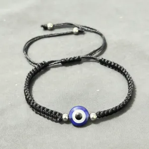 Gros plan détaillé d'un bracelet tressé noir avec un œil turc et des perles métalliques.