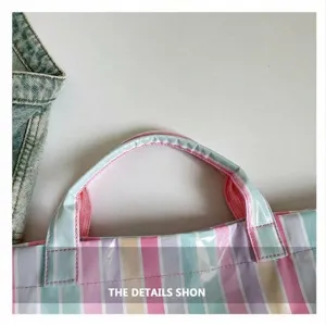 Close-up detail of the durable striped PVC tote bag handle and waterproof material texture.