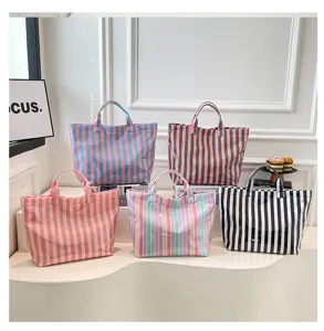 Detailed view of colorful PVC striped tote bags displayed on a clean white shelf.