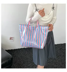 Detailed view of the transparent PVC tote bag featuring vibrant pink and blue vertical stripes.