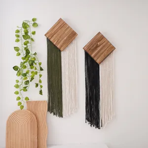 Vue detaillee de la tenture murale boheme faite main en bois et pompons pour decoration.