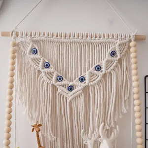 Bohemian handmade macrame wall hanging decor with evil eye beads and wooden rod.