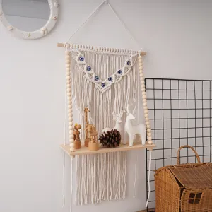 Bohemian handmade cotton macrame wall hanging shelf with evil eyes and wooden beads detail.