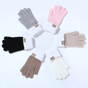 Detailopname van gebreide winterhandschoenen met witte pluche manchetten en labels.
