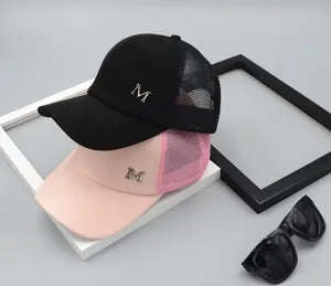 Detail shot of summer mesh baseball caps in black and pink with metal M letter logo.