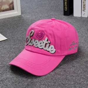 Pink baseball cap detail showing glitter Sweetie embroidery and side lettering close up.